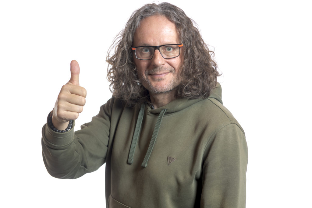 Autoportrait de David Casartelli sur fond blanc faisant le pouce en haut